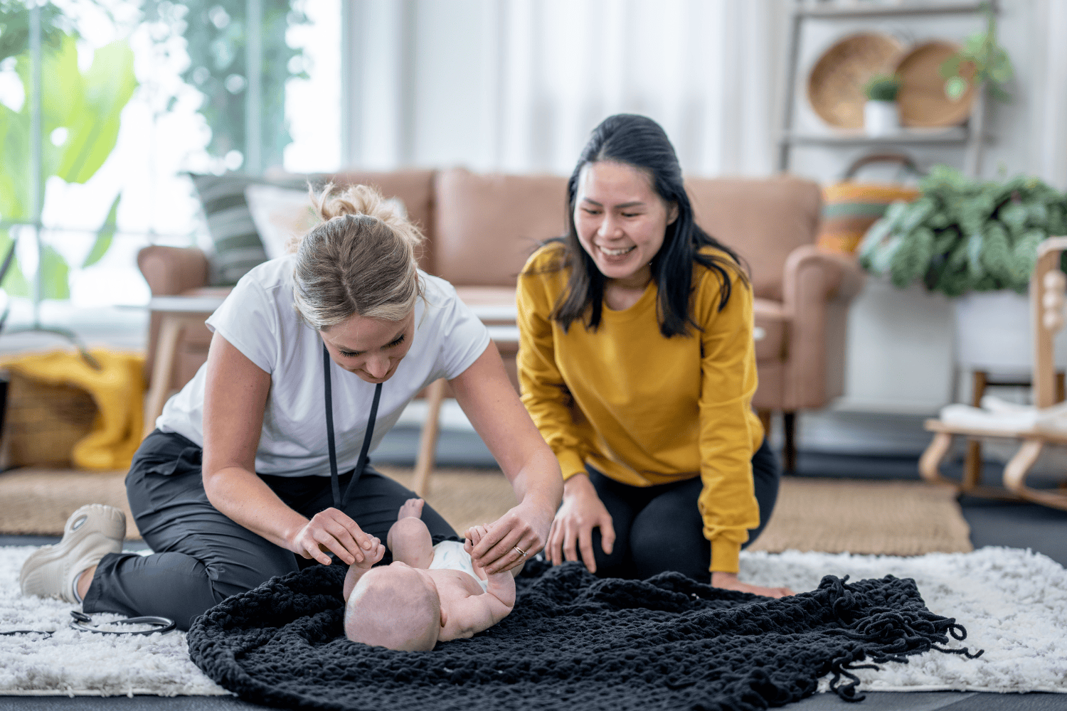 A woman and a girl practicing infant CPR on a baby doll in a cozy living room.